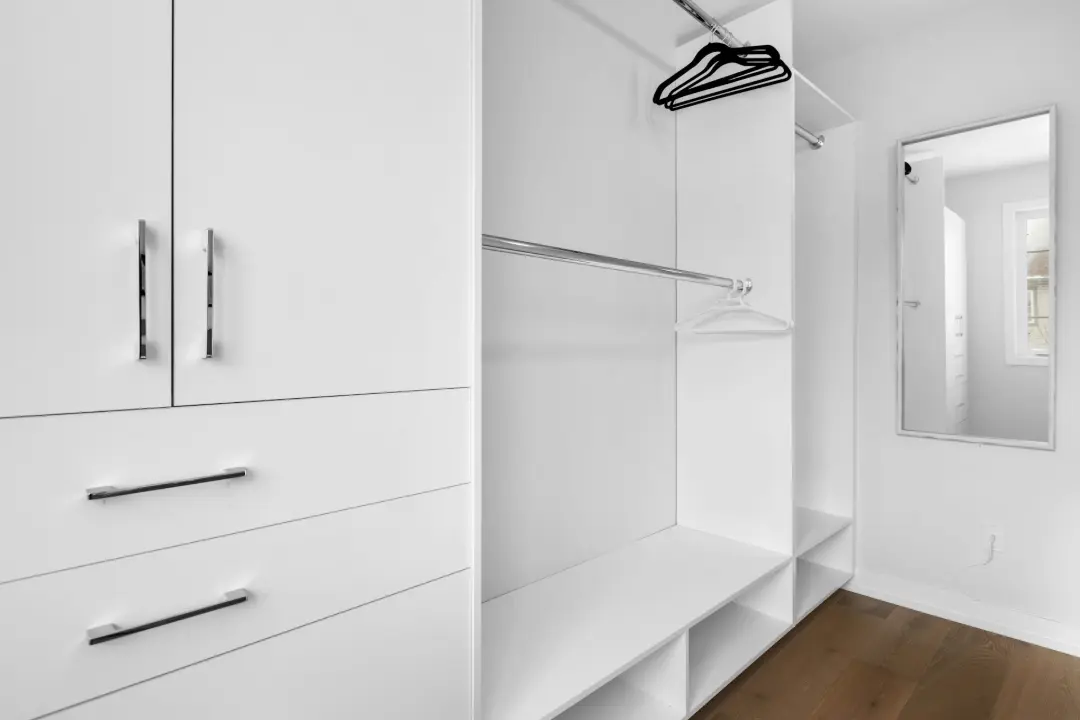 a walk in closet with white cabinets and drawers