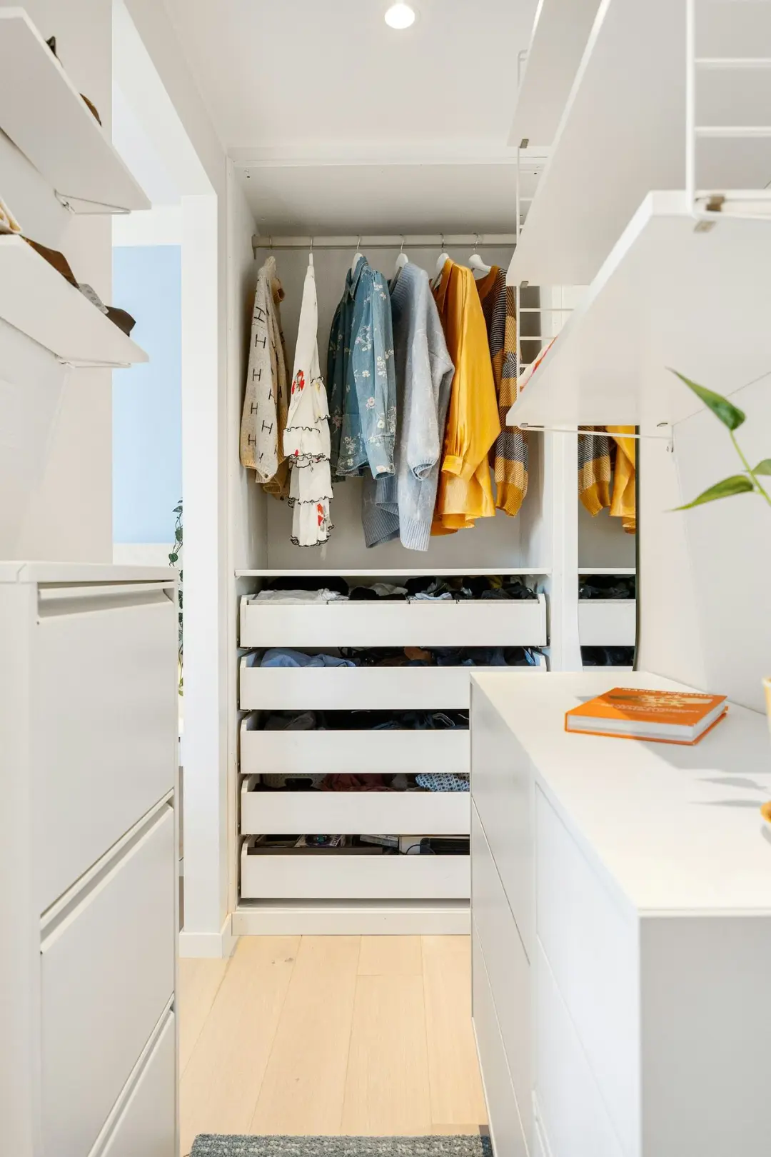A walk in closet with white cabinets and drawers