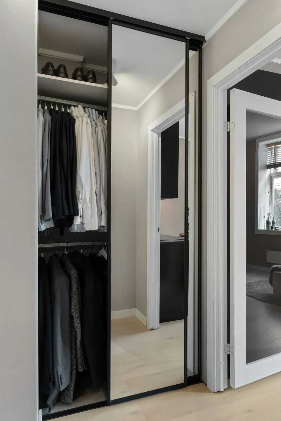 A walk in closet with mirrored doors and a mirror