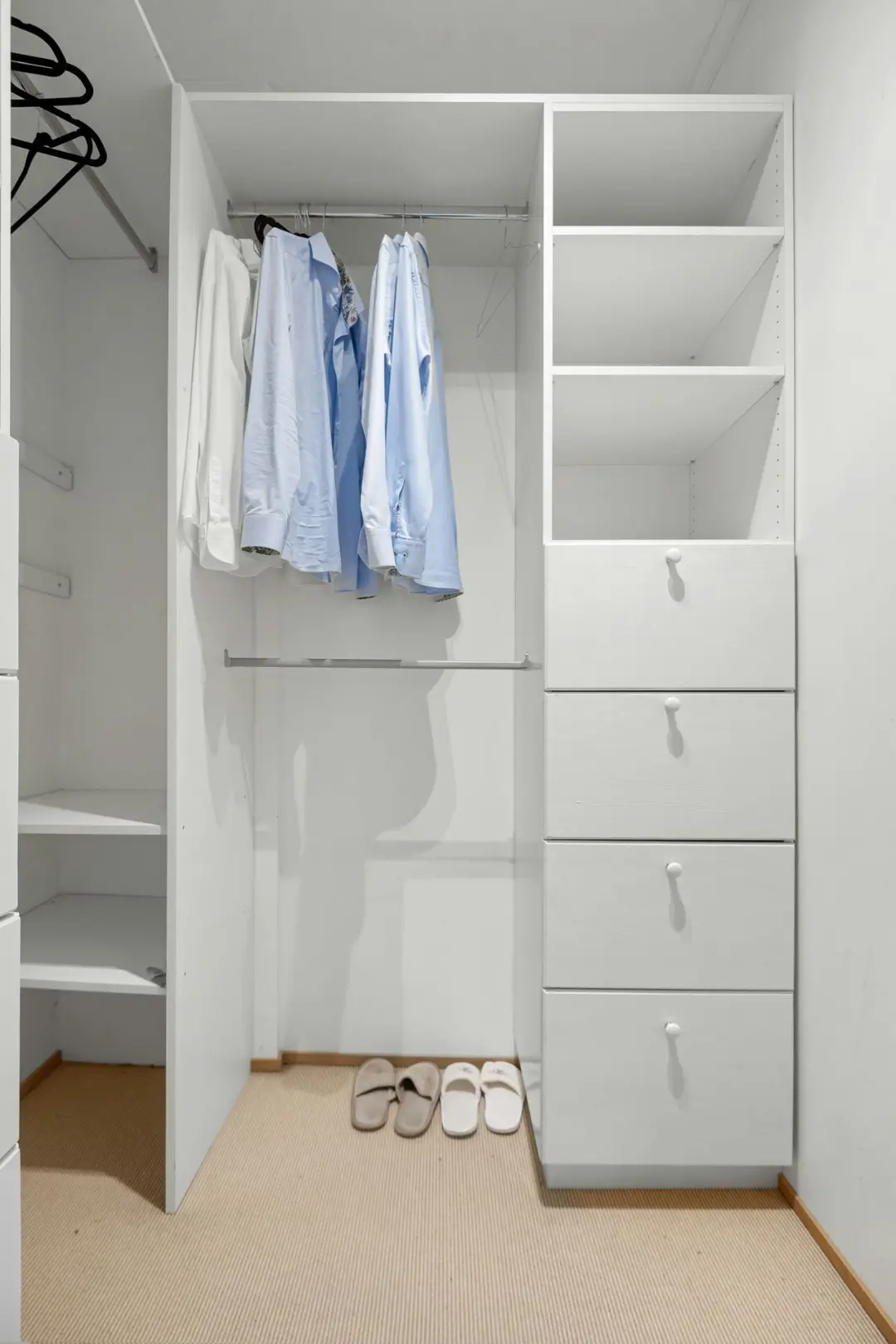 A white closet with a pair of shoes on the floor